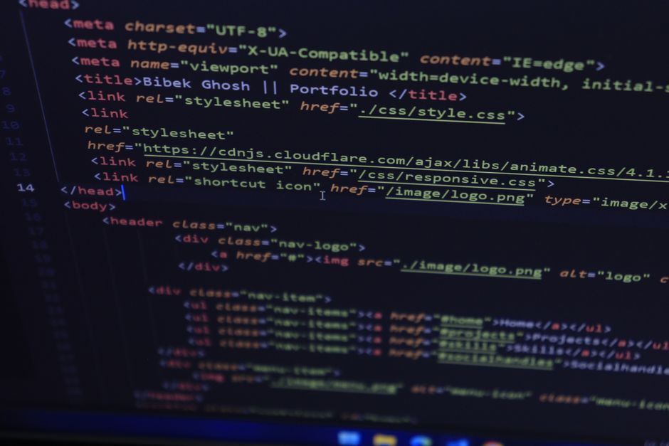 Close-up view of a computer screen displaying HTML code with colored syntax highlighting, including tags such as <ul>, <li>, <a>, and <div>. The code appears to be part of a website’s layout, featur